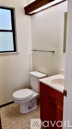 A small bathroom with a toilet, sink, and a window.