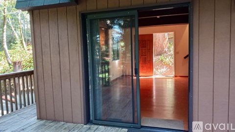 A wooden deck with a glass door leading to a room.