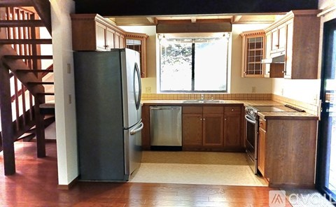 A black refrigerator is in a kitchen with wooden cabinets.