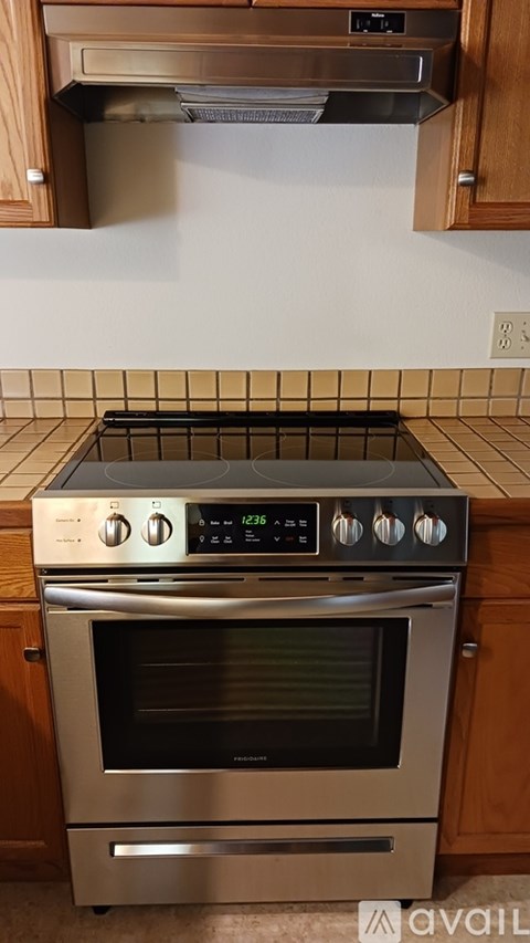A modern stainless steel oven with a digital display and control knobs is installed in a kitchen.