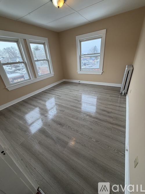 A bathroom with a toilet, shower, and a window.