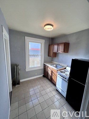 A kitchen with a black refrigerator, white oven, and brown cabinets.