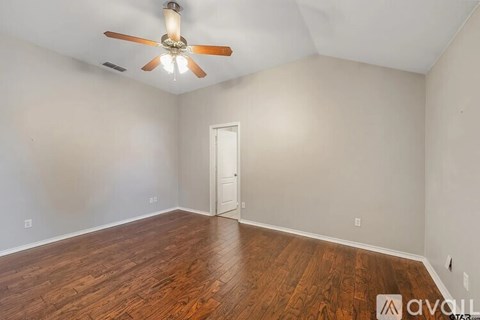 A room with a ceiling fan and wooden flooring.
