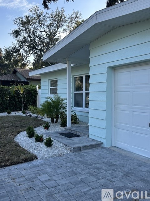 A white house with a garage door and a small garden in front.