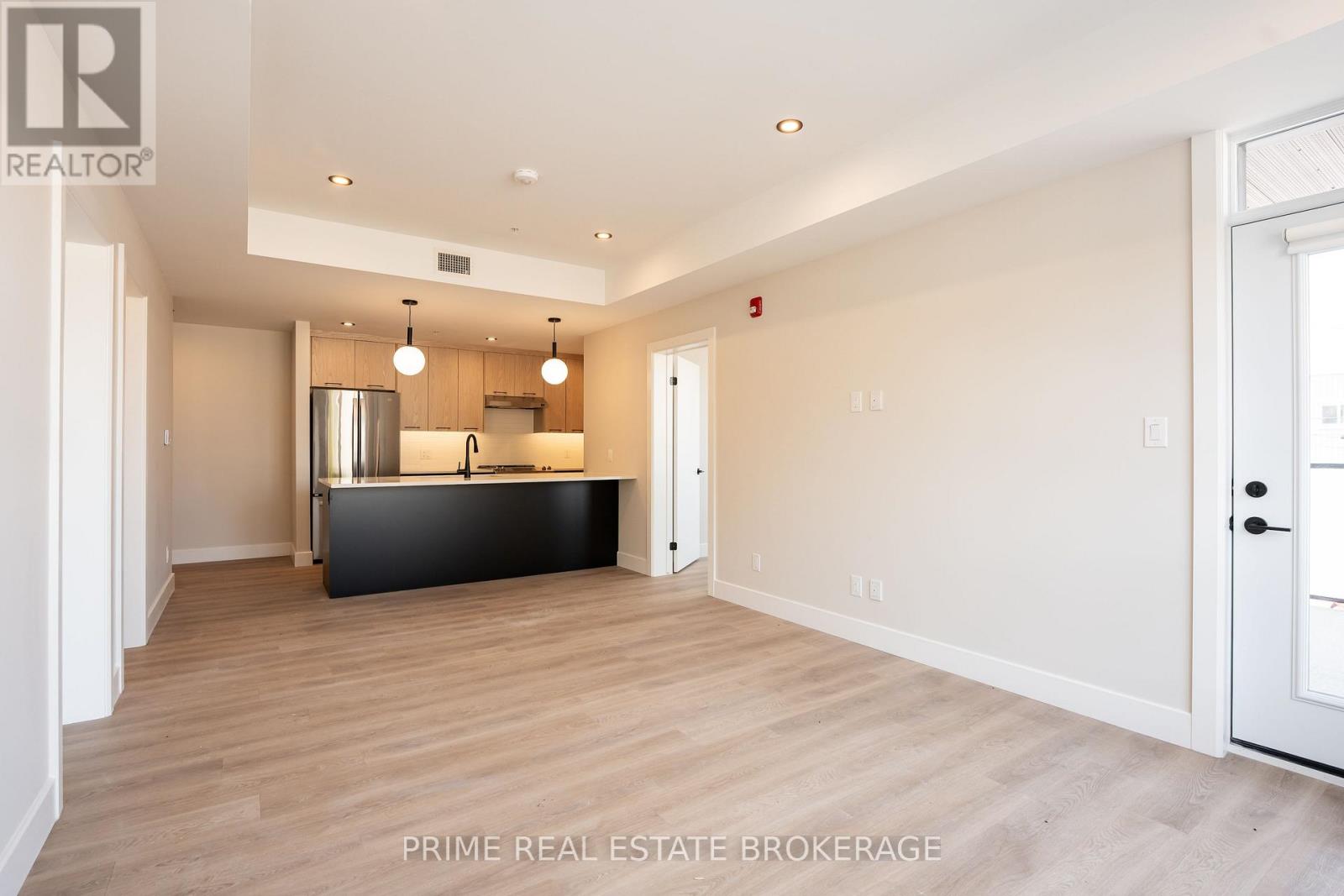 A spacious kitchen with a black countertop and wooden flooring.