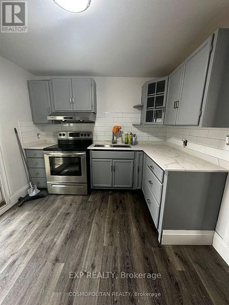 A kitchen with wooden floors and grey cabinets.