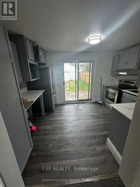 A kitchen with a refrigerator, oven, and microwave.