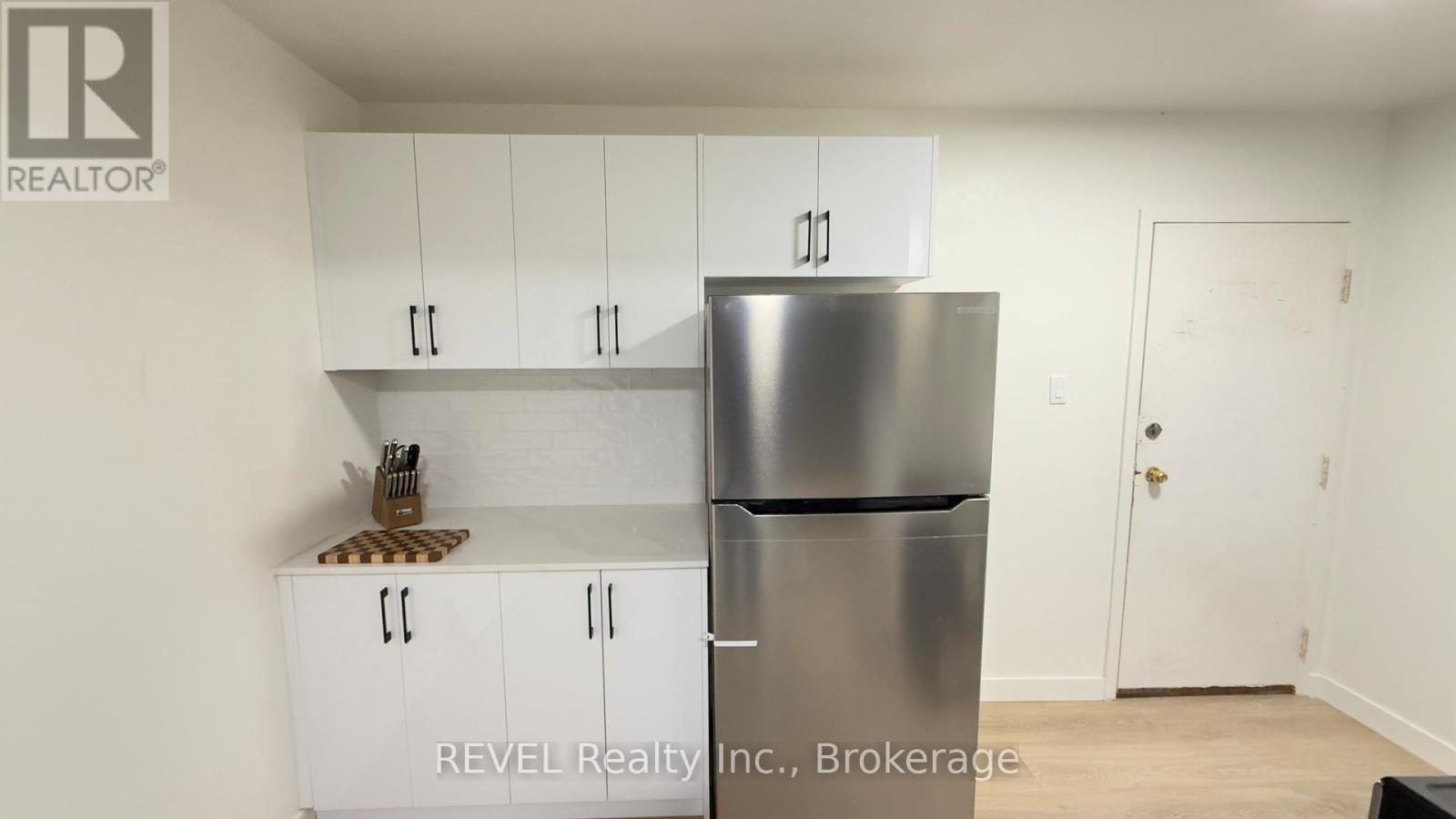 A kitchen with white cabinets and a stainless steel refrigerator.