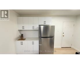 A kitchen with white cabinets and a stainless steel refrigerator.