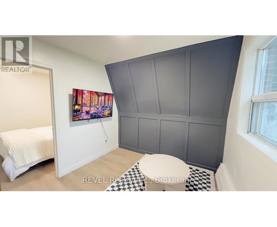 A bedroom with a bed, a painting, and a checkered floor.