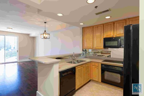 A kitchen with wooden cabinets and a black refrigerator.