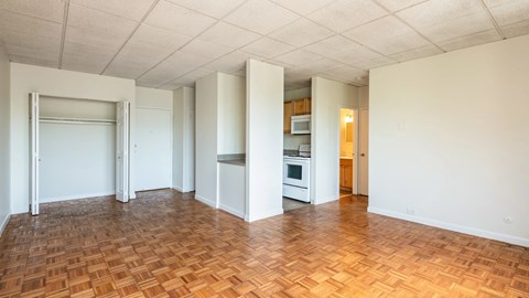 Spacious living area with parquet flooring, open closet and kitchen view at 929 Mass Apartments.
