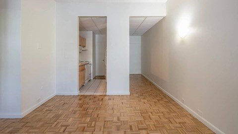 Open living layout with parquet flooring and view into the kitchen at 929 Mass Apartments.
