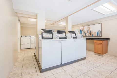 A white kitchen with a black counter and a brown trash can.