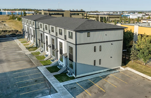 A large grey building with a parking lot in front.