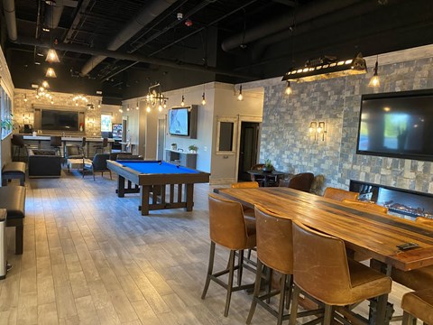 A room with a pool table and bar stools.