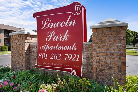 A sign for Lincoln Park Apartments is displayed in front of a brick wall.