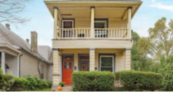 A yellow house with a red door and a balcony.