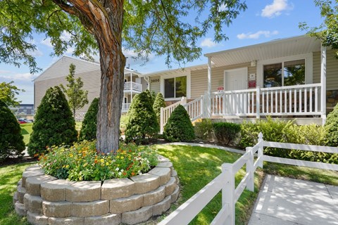 A house with a white picket fence and a tree in front.