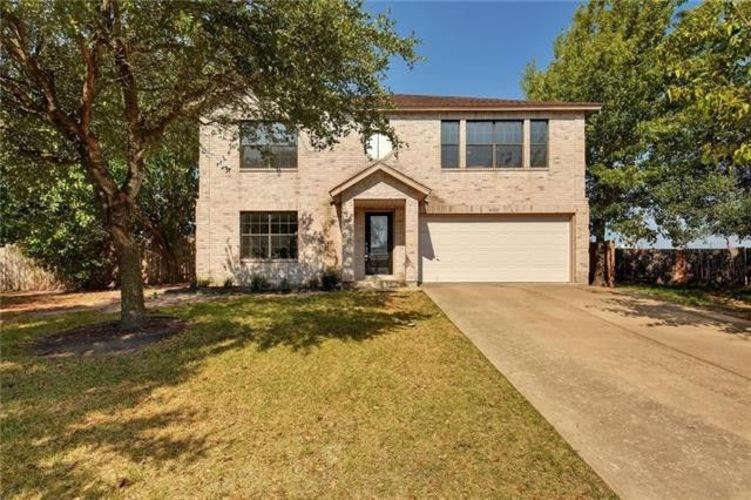 A house with a driveway and a tree in front.
