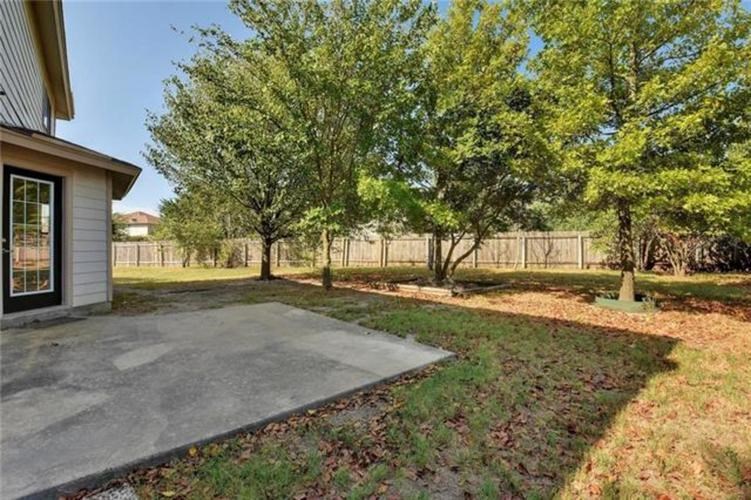 A concrete patio is surrounded by a fence and trees.