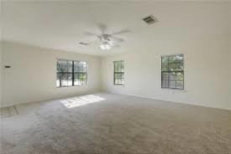 A spacious room with a ceiling fan and two windows.