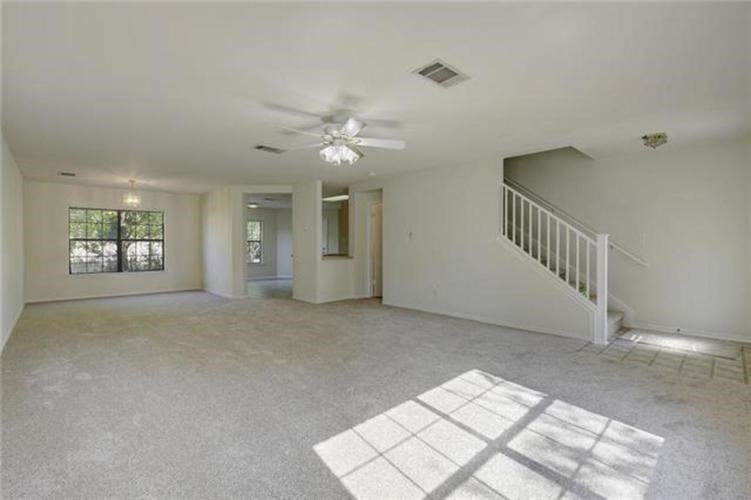 A spacious room with a staircase and a ceiling fan.