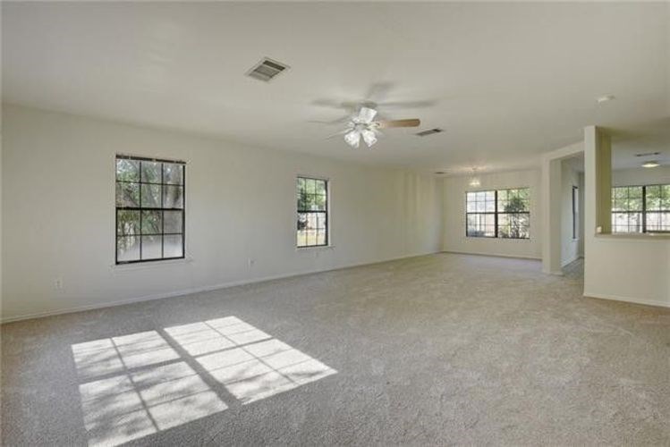 A spacious room with a ceiling fan and windows.