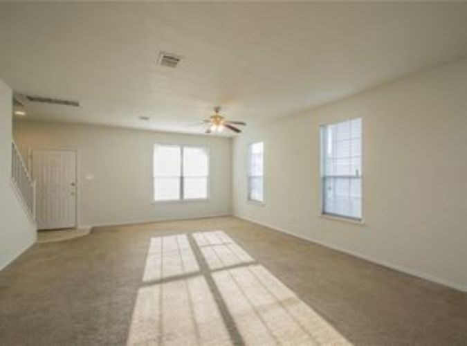 A spacious room with a rug on the floor and a ceiling fan.
