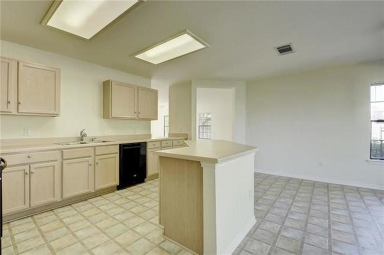 A kitchen with a black trash can and a window.