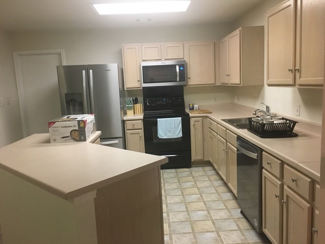 A kitchen with a white counter and black appliances.