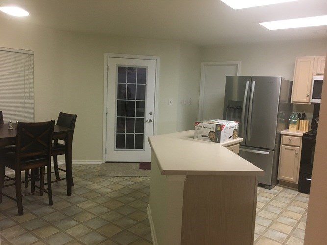 A kitchen with a table and chairs and a refrigerator.