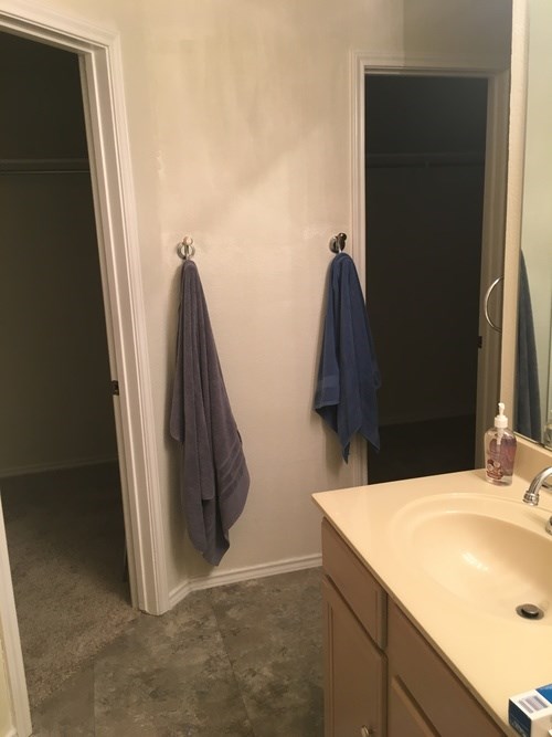 A bathroom with a sink, mirror, and towel rack.
