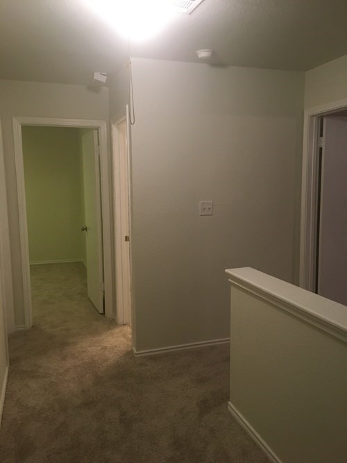 A room with a carpeted floor and a doorway leading to another room.