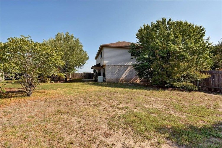 A house with a white fence and a tree in front of it.