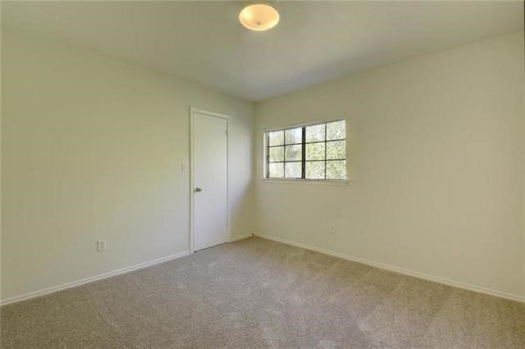 A room with a carpeted floor, a door, and a window with blinds.