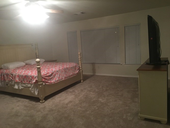 A bedroom with a bed, dresser, and television.