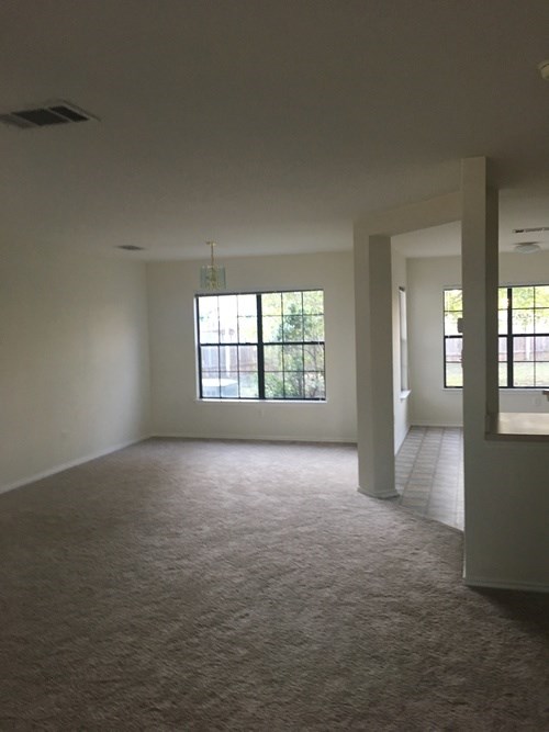 A room with a carpeted floor and a window with bars on it.