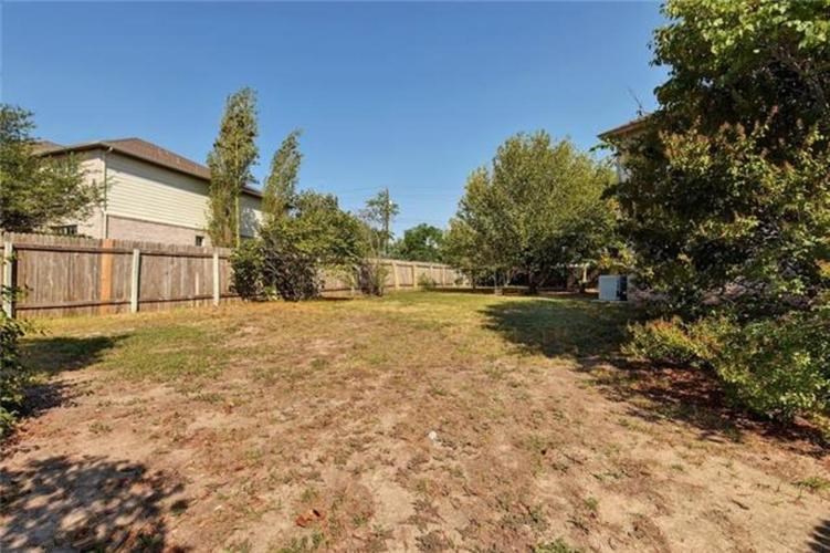A backyard with a dirt area and a fence.