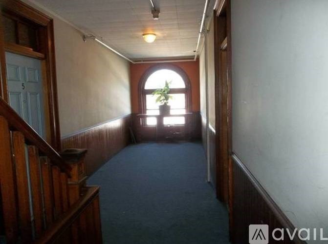 A hallway with a wooden staircase and a window with a plant in it.