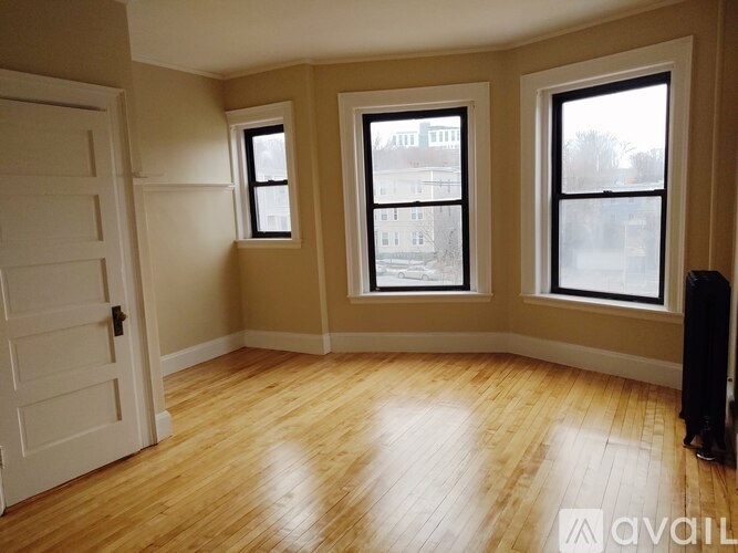 A room with wooden floors and three windows.