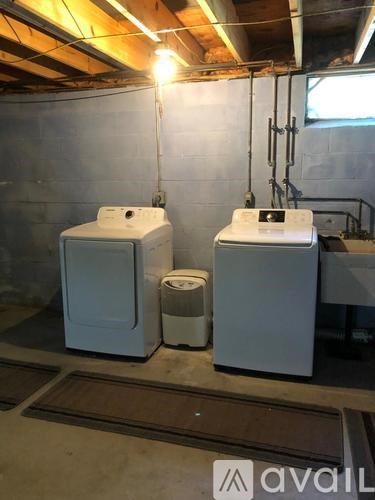 Two white washing machines in a basement.