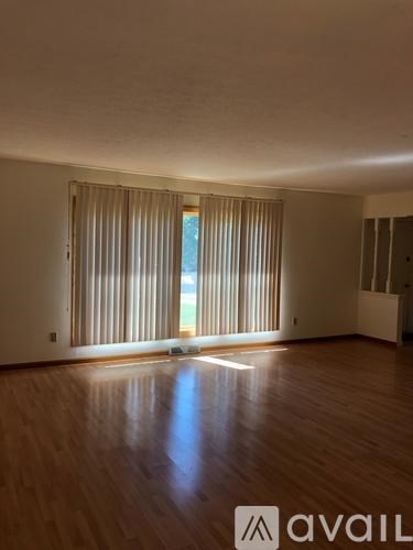 A room with wooden floors and a window with blinds.