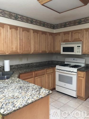 A kitchen with wooden cabinets and a granite countertop.