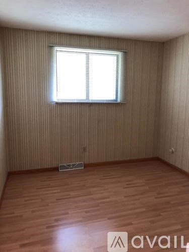 A room with wooden flooring and a window with blinds.
