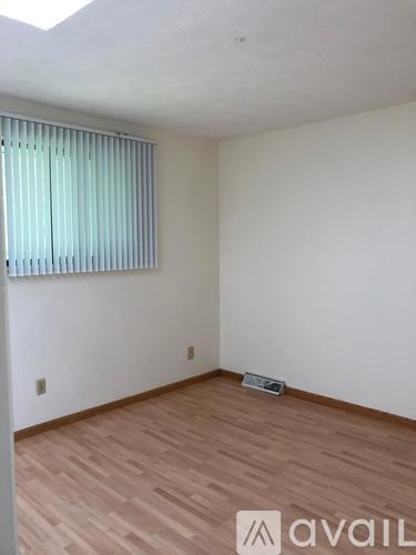 A room with wooden flooring and a window with blinds.