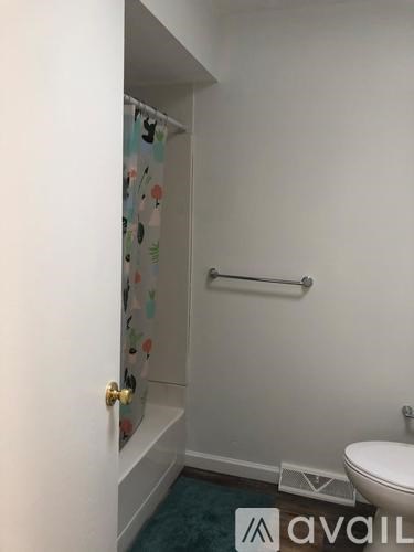 A bathroom with a toilet, a shower curtain, and a towel rack.
