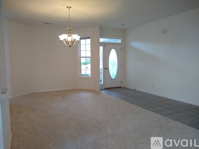 A room with a chandelier, carpeted floor, and a door with a window.