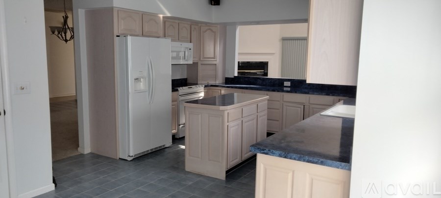 A kitchen with a white fridge and a black counter top.
