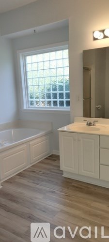 A bathroom with a tub, sink, and window.